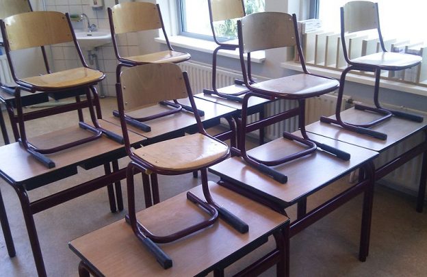 An empty classroom with chairs on the desks