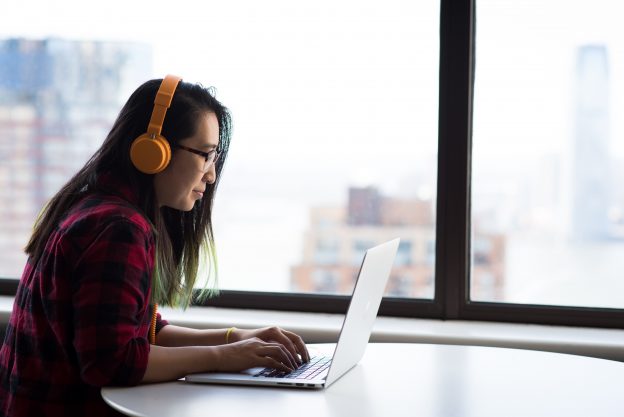 Woman using a laptop wearing headphones