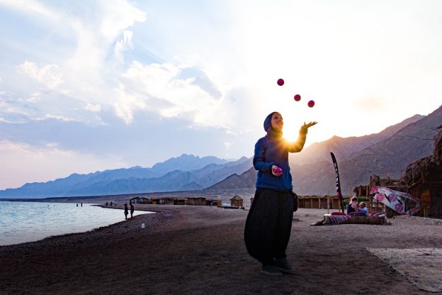 woman juggling with the sun behind her